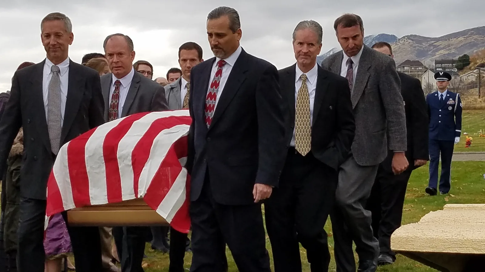 Honor guard carrying a flag-draped casket at a military funeral