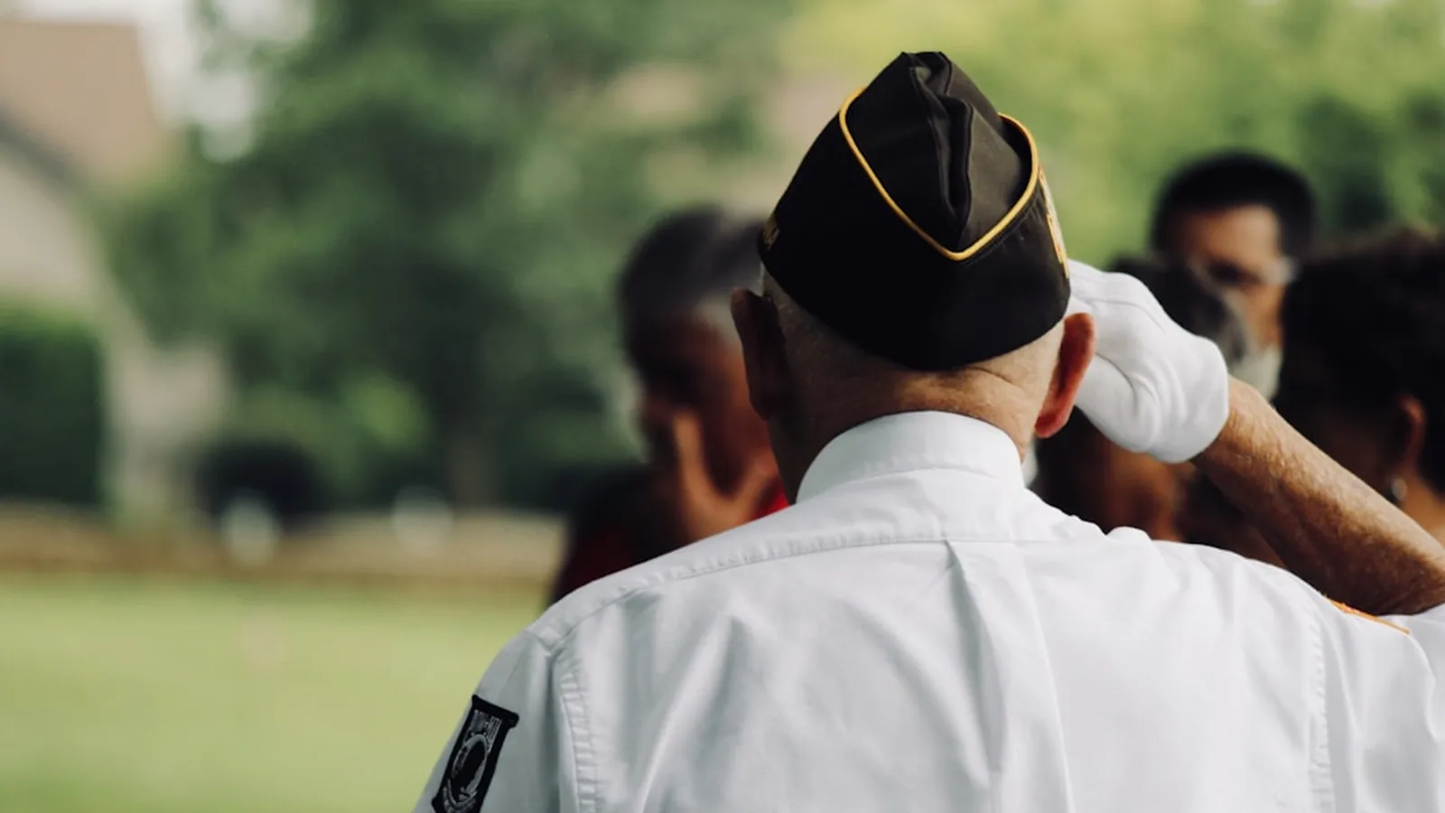 A veteran in uniform saluting at a memorial service