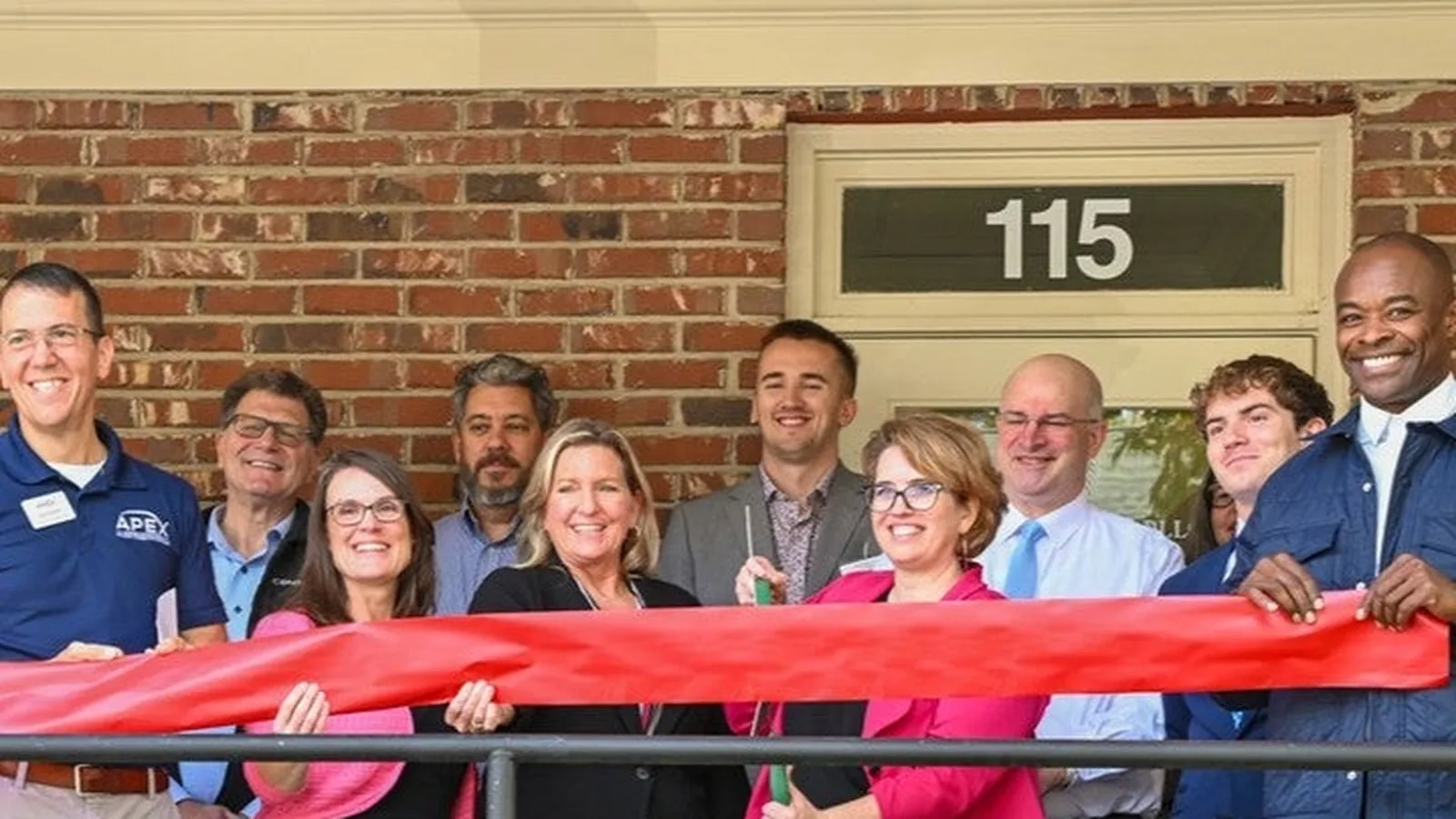 Deb Rasmussen and guests at the firm's ribbon cutting outside the Apex office