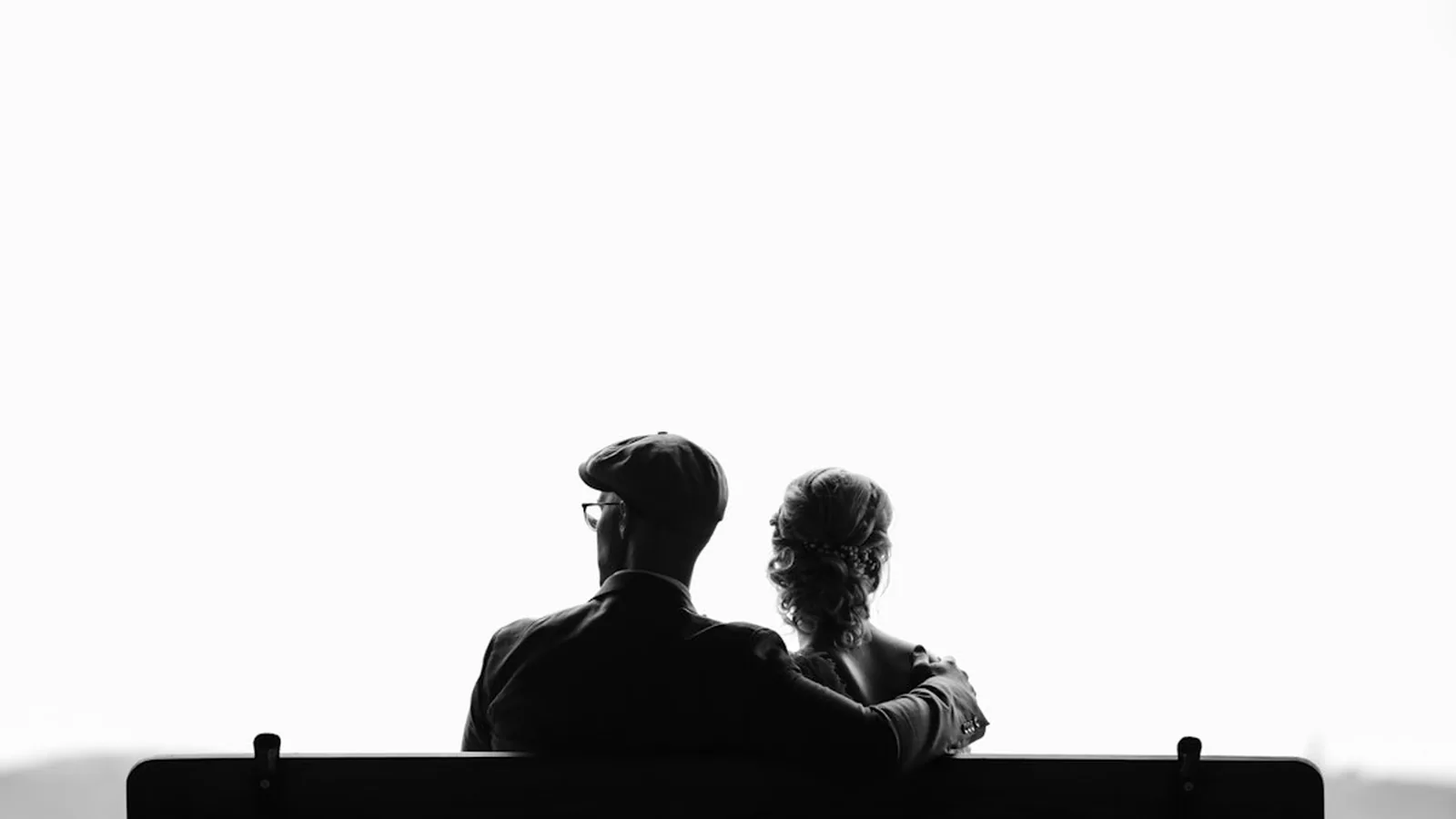 Silhouette of an older couple sitting close together on a bench